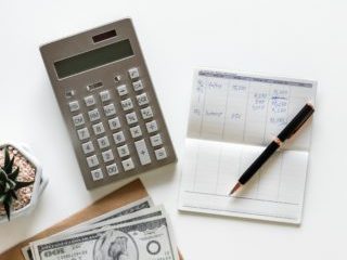 calculator, stack of US bills and a balance book referencing income