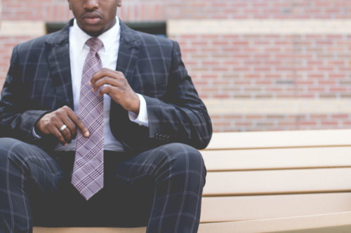man sitting on a bench adjusting his tie