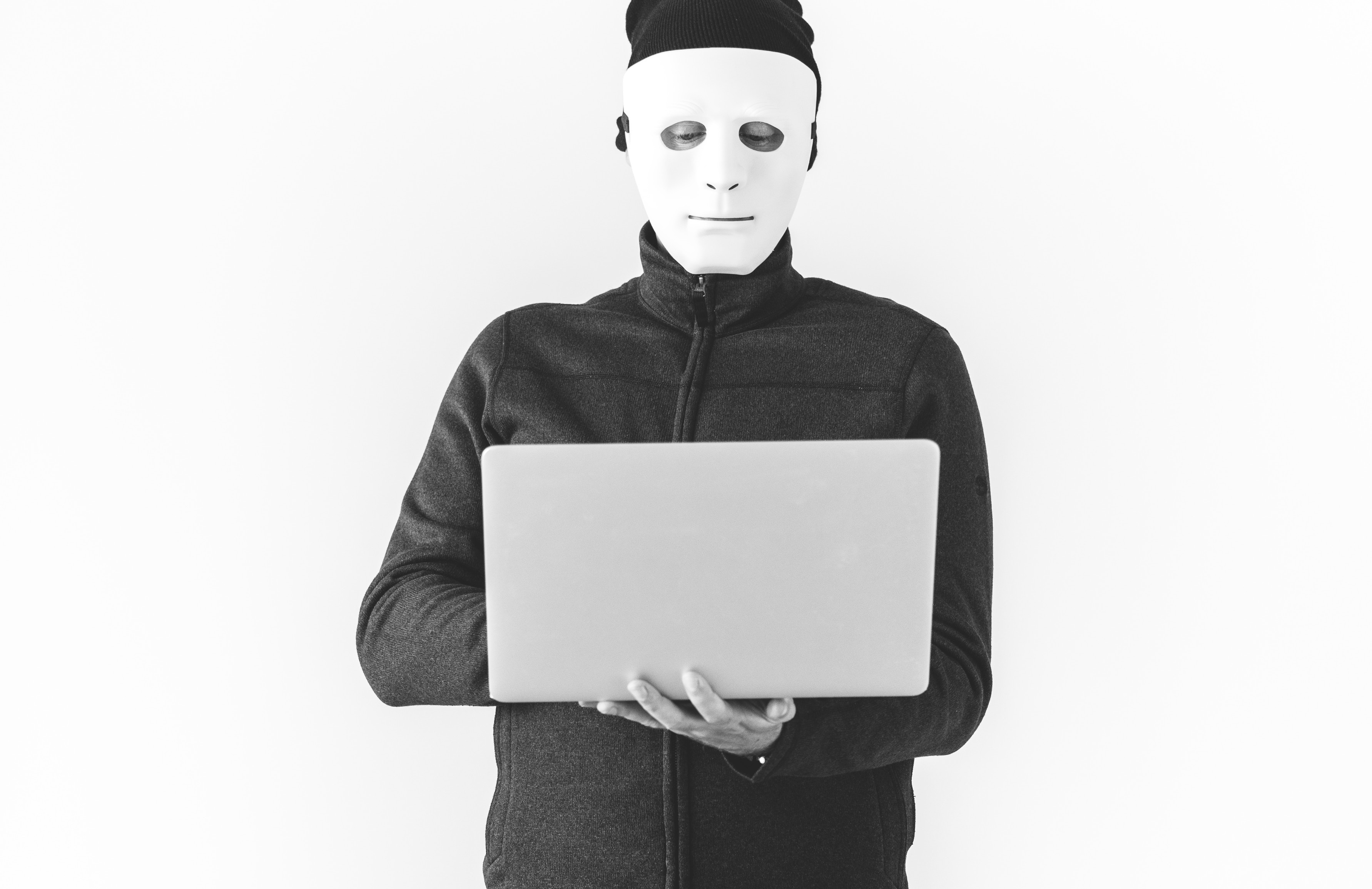 hacker with a face mask on holding a laptop
