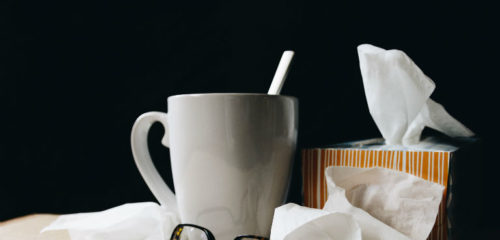 white ceramic mug on white table beside black eyeglasses