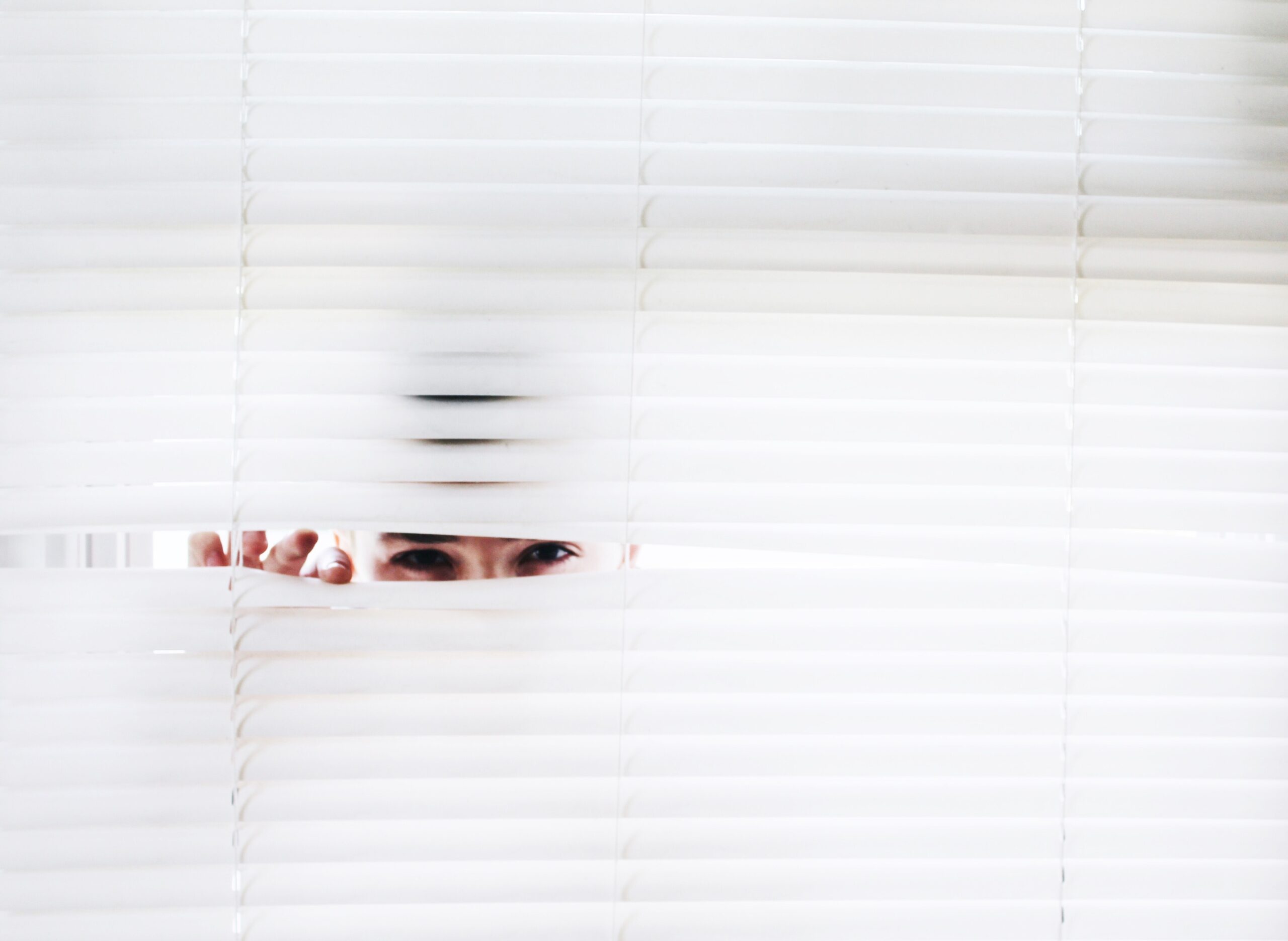 man hiding behind blinds